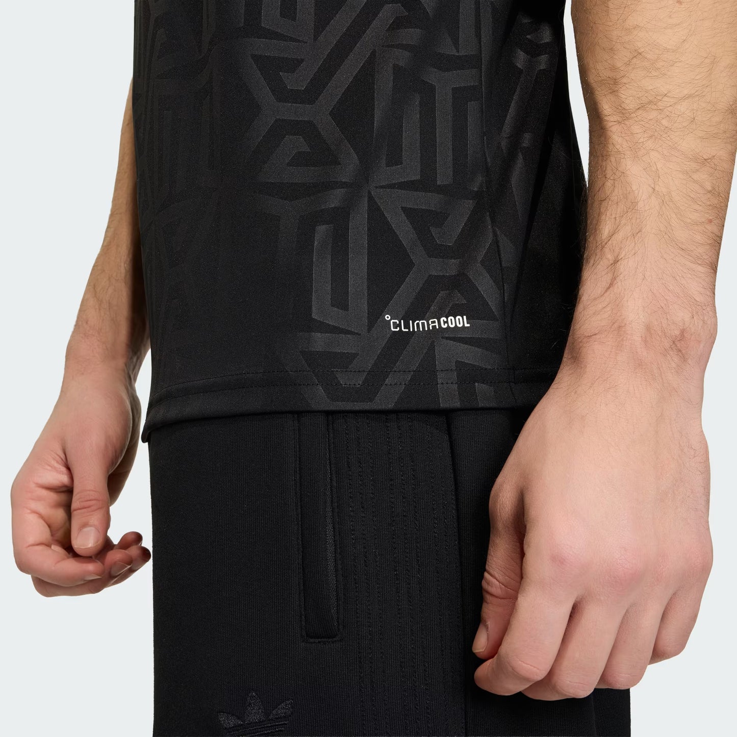 Person wearing a black sleeveless shirt with geometric pattern and 'ClimaCool' text, standing against a white background.