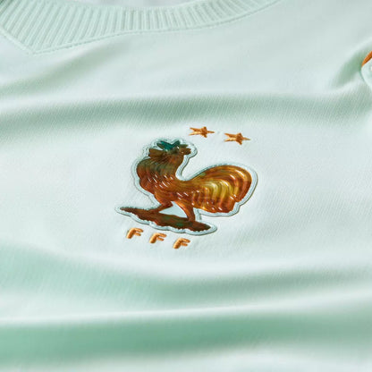 Close-up of a rooster emblem on a light green sports jersey with 'FFF' branding.