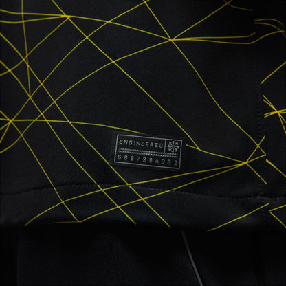 Black fabric with yellow geometric lines and a branded label on a black background