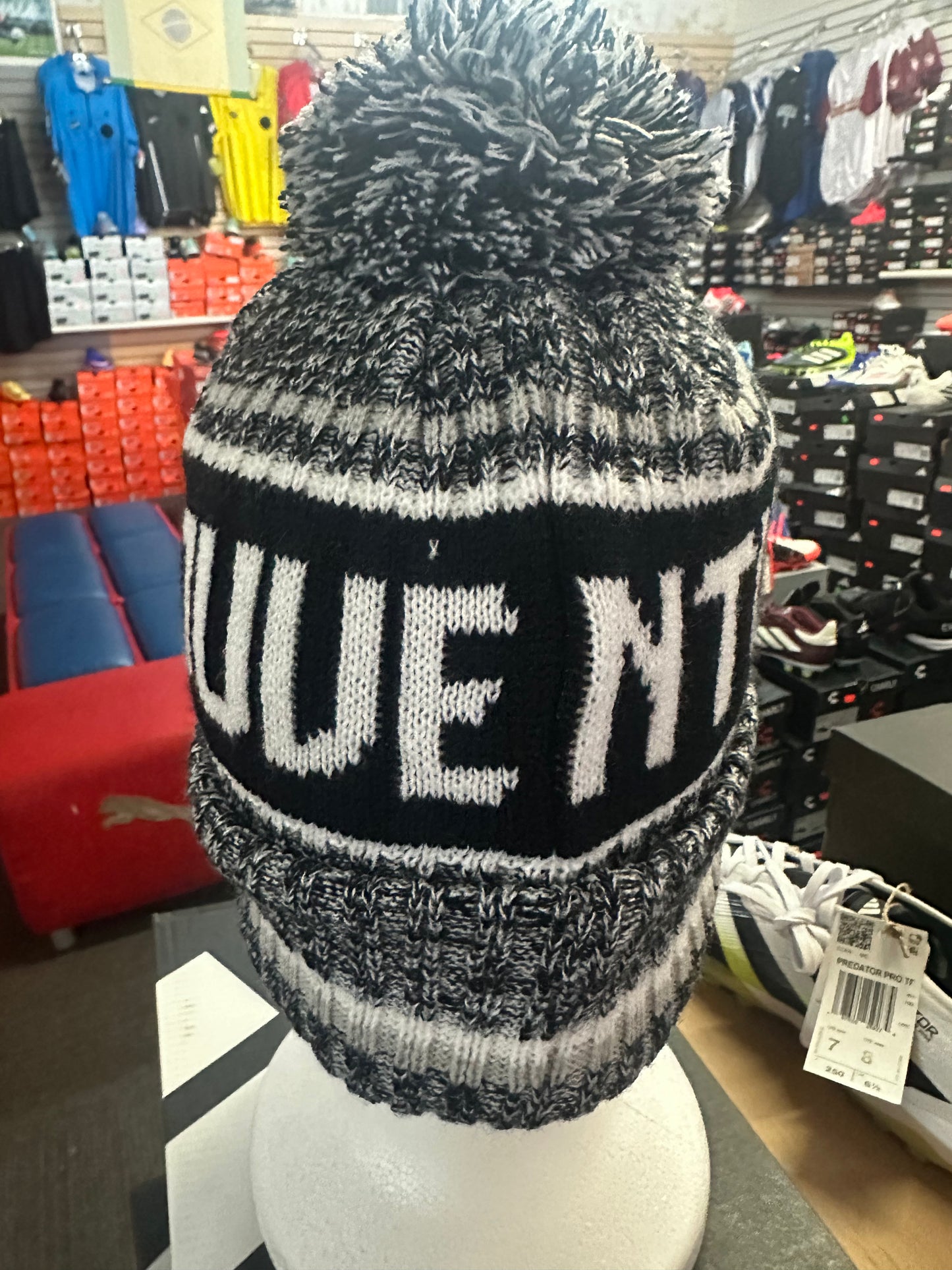Black and white knit beanie with 'Juventus text on a mannequin head in a store setting.