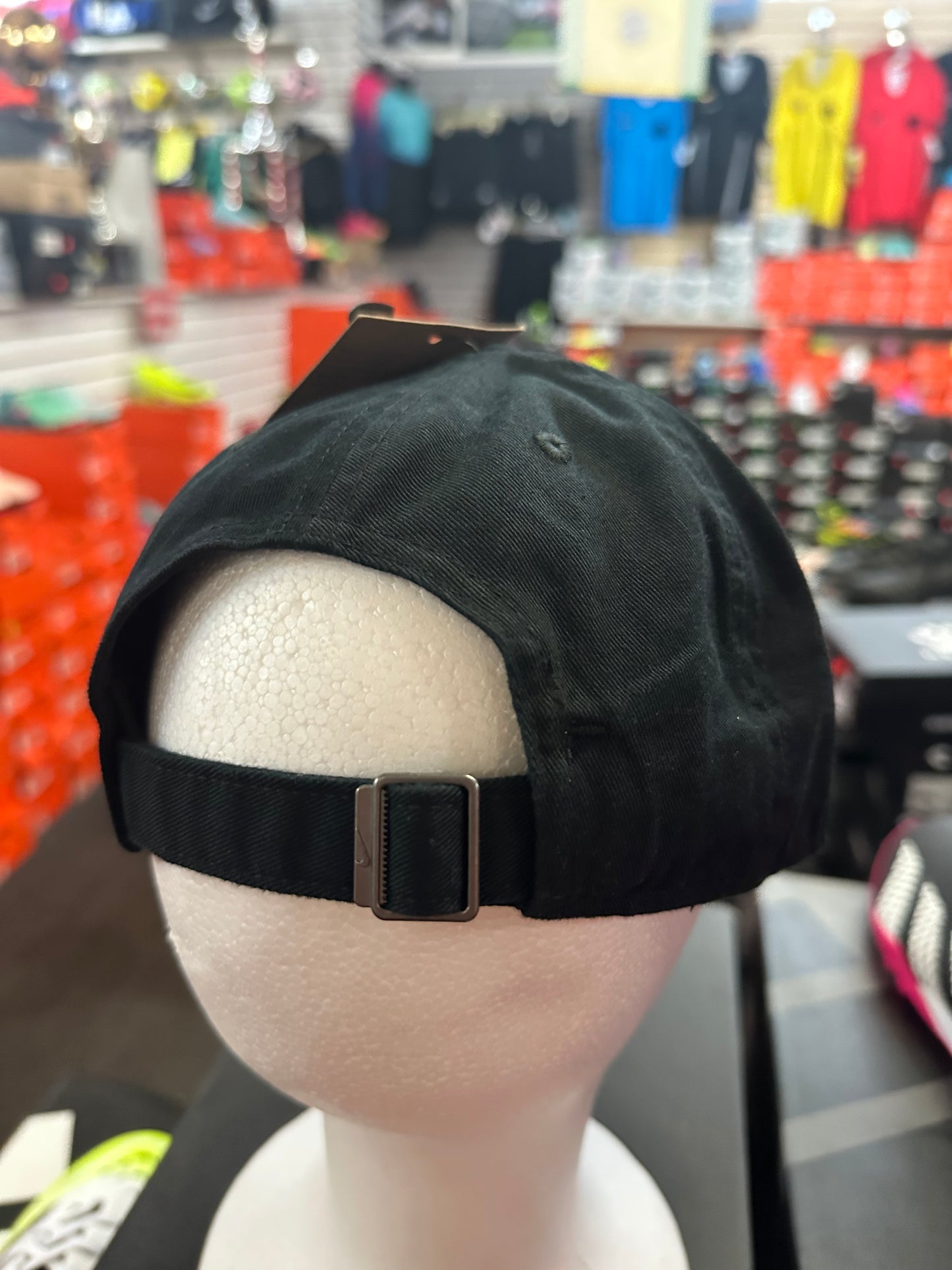 Black cap held by a hand with a blurred store background