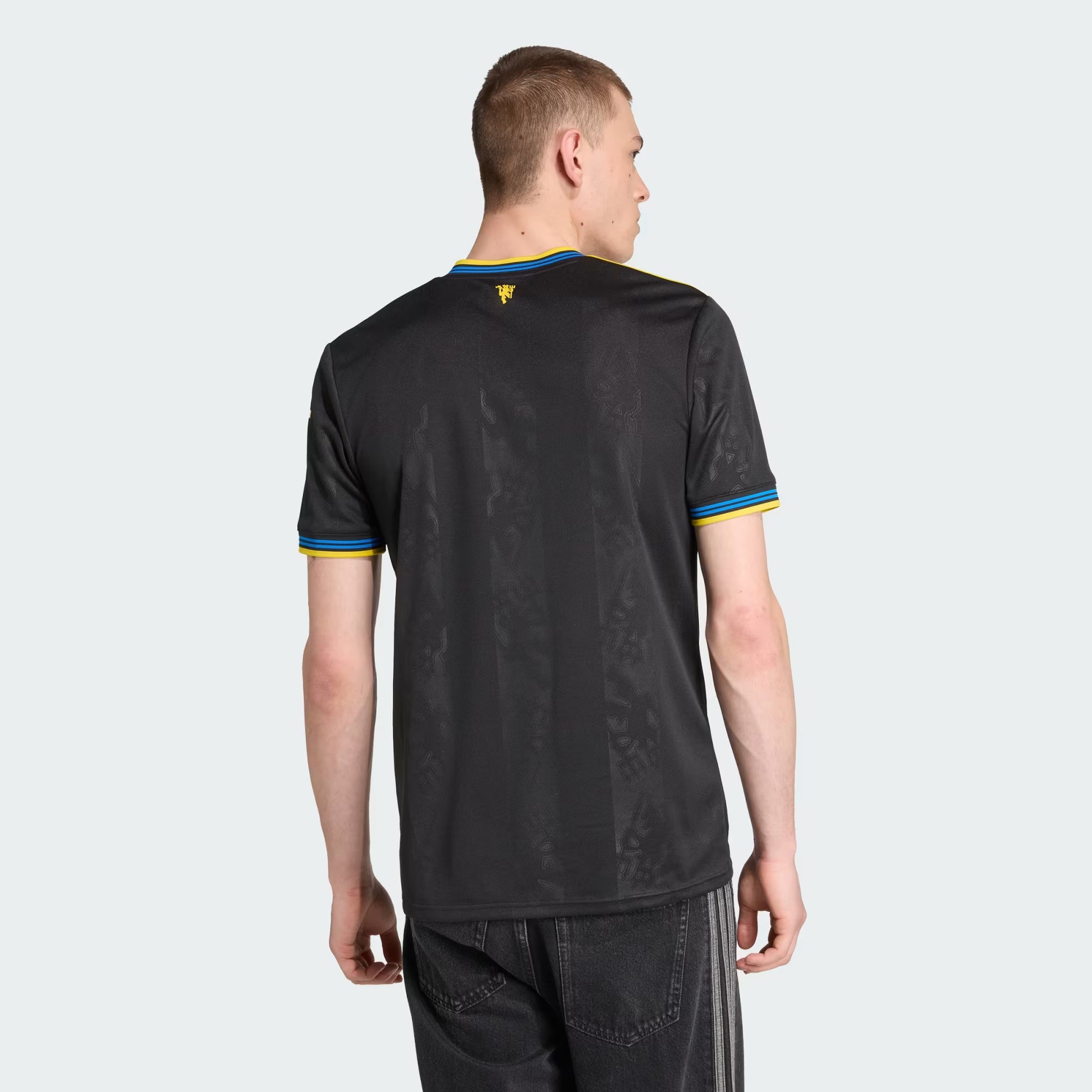 Person wearing a black sports jersey with yellow and blue accents on a white background