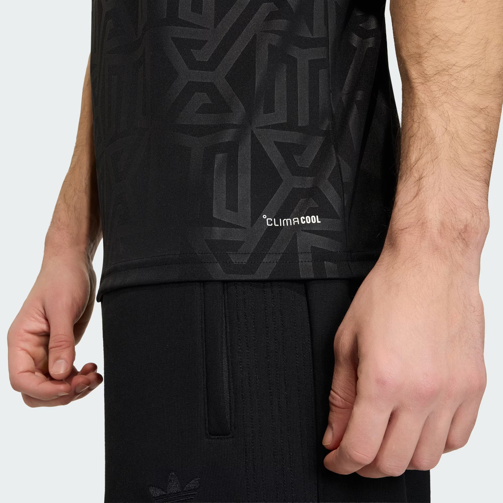 Person wearing a black sleeveless shirt with geometric pattern and 'ClimaCool' text, standing against a white background.
