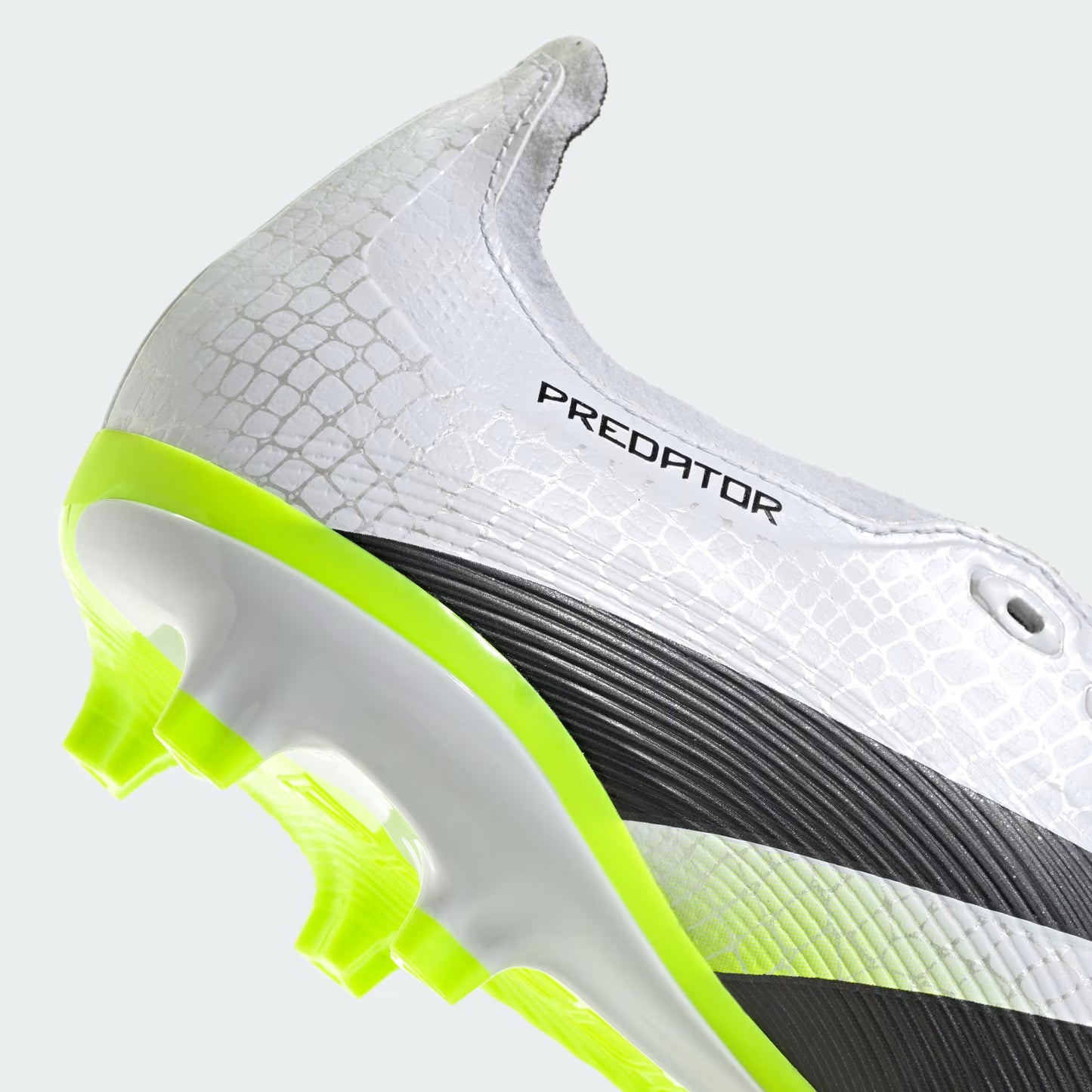 Close-up of a white soccer cleat with green sole on a light gray background